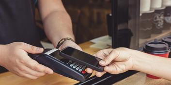 The future of payment: a person paying via TWINT with a cell phone held to a card reader.