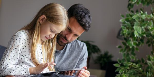 Vater und Tochter lernen am Tablet alles rund ums Geld. 