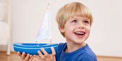 Freudiger Junge mit Spielzeug-Segelschiff