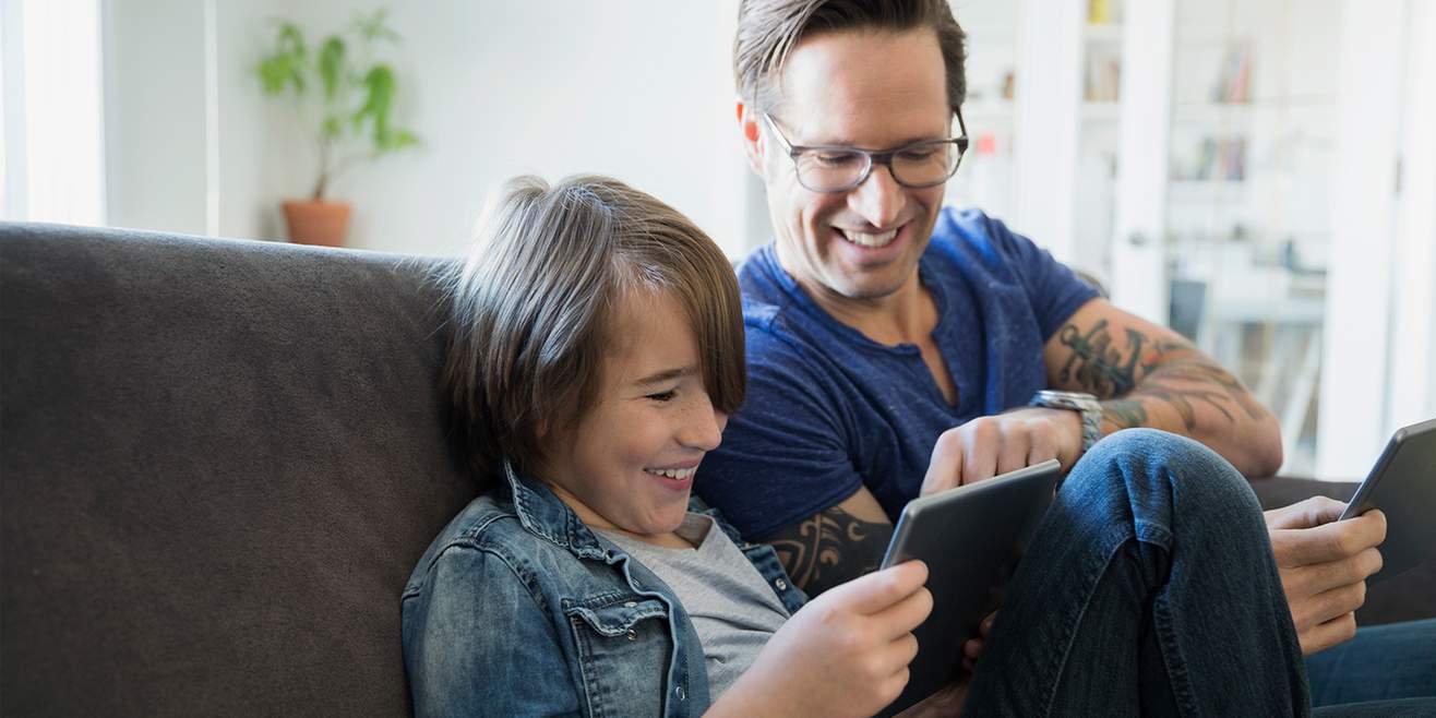 Le trappole su Internet: padre e figlio osservano insieme il tablet.